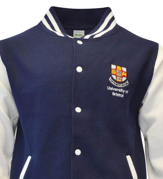 A close up of the top half of a baseball jacket with a navy torso and white sleeves. There is navy and white stripes around the collar, white buttons down the front and the crest of the University of Bristol over the left chest.